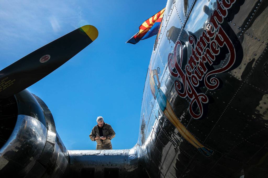 Crew Chief Dennis Fennessey stands on the wing of Sentimental Journey, a Boeing B-17 Flying Fortress, after a morning flight on Monday, at Arlington Municipal Airport in Arlington. (Ryan Berry / The Herald)