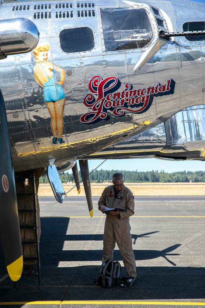 Brian Churchill, captain of Sentimental Journey, a Boeing B-17 Flying Fortress, stands underneath the bomber on Monday, at Arlington Municipal Airport in Arlington. (Ryan Berry / The Herald)