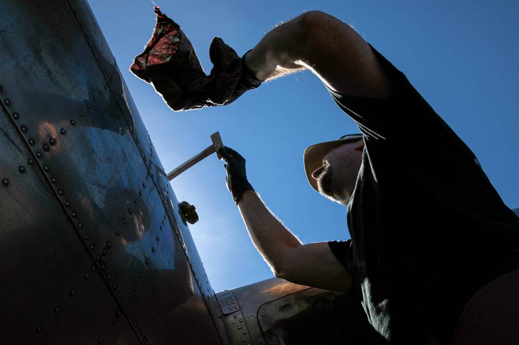 Robert Rocky Racoosin checks the oil in each of Sentimental Journeys four engines after the bomber landed on Monday, Aug. 15, 2022, at Arlington Municipal Airport in Arlington, Washington. (Ryan Berry / The Herald)