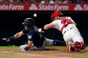 Seattle Mariners' Dylan Moore, left, scores past Los Angeles Angels catcher Max Stassi on a ground ball from Ty France during the ninth inning of a baseball game Monday, Aug. 15, 2022, in Anaheim, Calif. (AP Photo/Marcio Jose Sanchez)