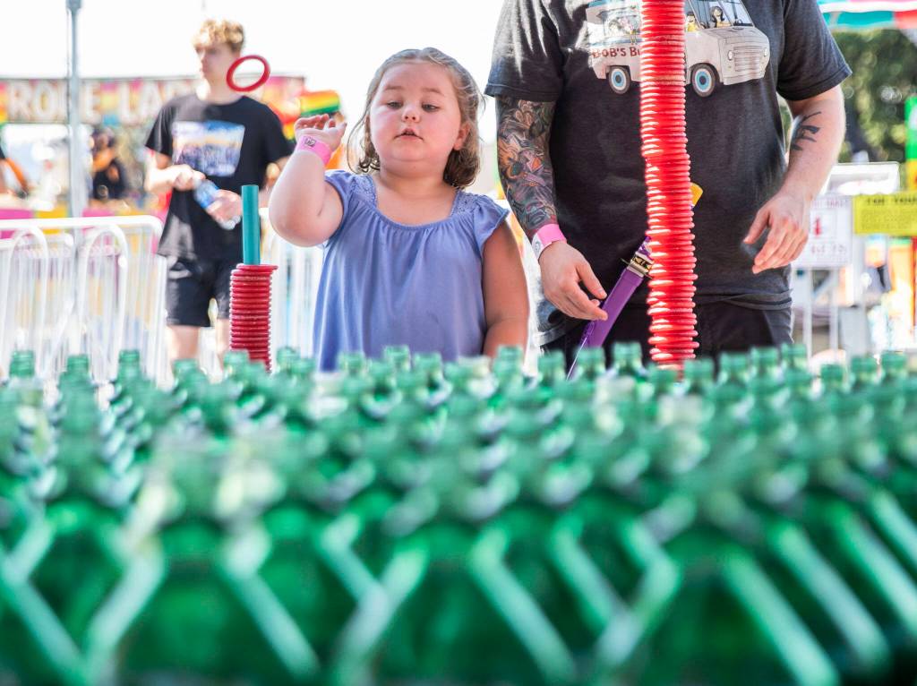 Zoey Allen, 5, plays ring toss with her dad during opening day of the Evergreen State Fair on Thursday, in Monroe. (Olivia Vanni / The Herald)
