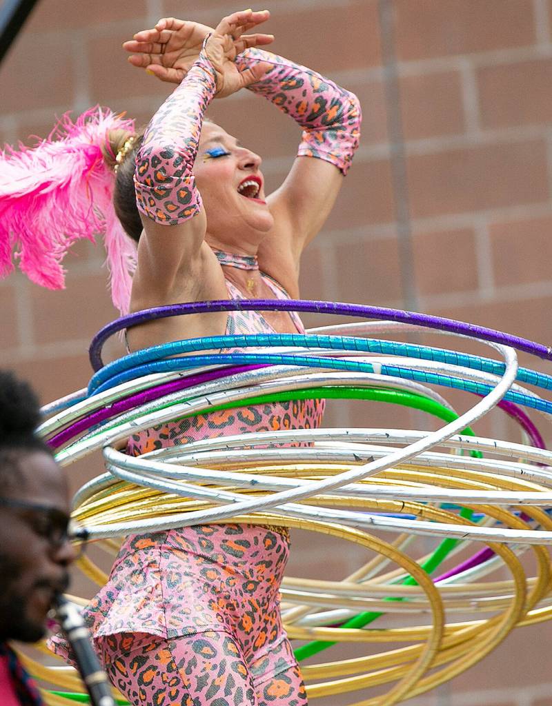 A performer hula hoops with well over a dozen hoops during Up Up Up Crane Circus evening performance Friday, in the empty lot at Hewitt and Oakes in downtown Everett. (Ryan Berry / The Herald)