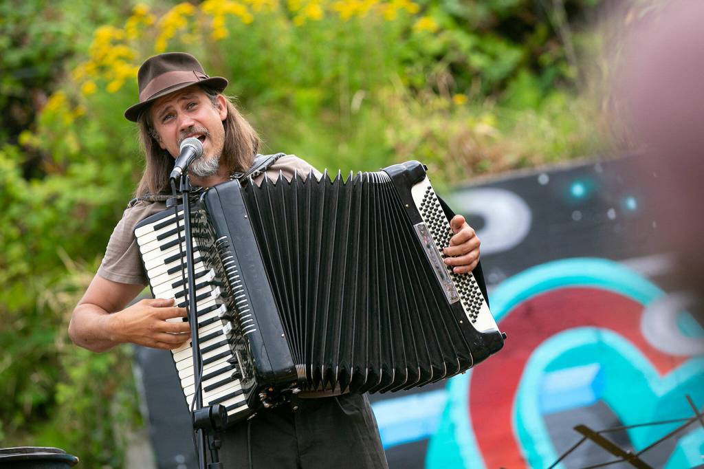 Jason Webley plays a sing-along song on accordion to get the crowd warmed up before Up Up Up Crane Circus evening performance Friday, in the empty lot at Hewitt and Oakes in downtown Everett. (Ryan Berry / The Herald)