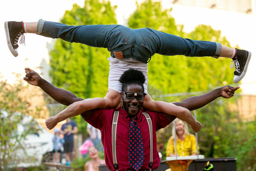 Two performers spin in circles during Up Up Up Crane Circus evening performance Friday, in the empty lot at Hewitt and Oakes in downtown Everett. (Ryan Berry / The Herald)