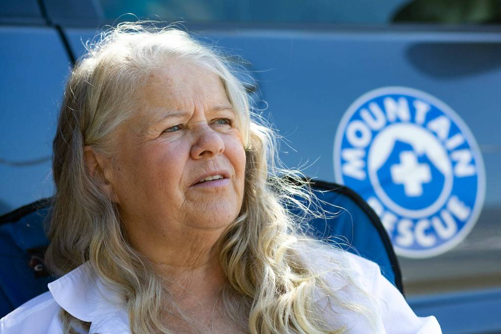 Suzanne Elshult sits beside her vehicle, which features a mountain rescue decal, on Wednesday, Aug. 17, 2022, at Meadowdale High School in Lynnwood. (Ryan Berry / The Herald)