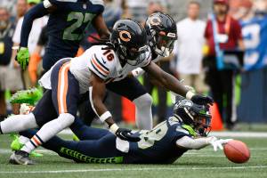 Seattle Seahawks' Cade Johnson, right, reaches for the ball after he fumbled on a punt return as Chicago Bears' Davontae Harris (16) and Dazz Newsome, upper right, reach for the ball during the first half of a preseason NFL football game, Thursday, Aug. 18, 2022, in Seattle. The ball was recovered by Bears' Elijah Hicks for a touchdown. (AP Photo/Caean Couto)