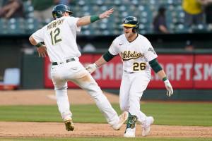 Oakland Athletics' Sheldon Neuse (26) is congratulated by Sean Murphy (12) after hitting into a fielder's choice that scored Tony Kemp during the 10th inning of a baseball game against the Seattle Mariners in Oakland, Calif., Saturday, Aug. 20, 2022. (AP Photo/Jeff Chiu)