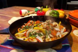 A sizzling cast iron pan of fajitas.