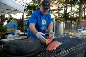Robert Keller adds fresh salmon to the grill for the Reefnet Festival salmon dinner on Lummi island on Aug. 20. (Hailey Hoffman/Cascadia Daily News)