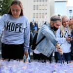Gina Anderson (left-right) and Rae Dorcas light candles as Shana Morcom gets a kiss from Tamara Cooper on Aug. 31, 2021, at a vigil at Snohomish County Campus Plaza in Everett honoring loved ones who have died from drug overdoses. (Kevin Clark / The Herald)