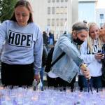 Gina Anderson (left-right) and Rae Dorcas light vigil candles as Shana Morcom gets a kiss from Tamara Cooper Tuesday afternoon at the Snohomish County Campus Plaza in Everett on August 31, 2021.  (Kevin Clark / The Herald)