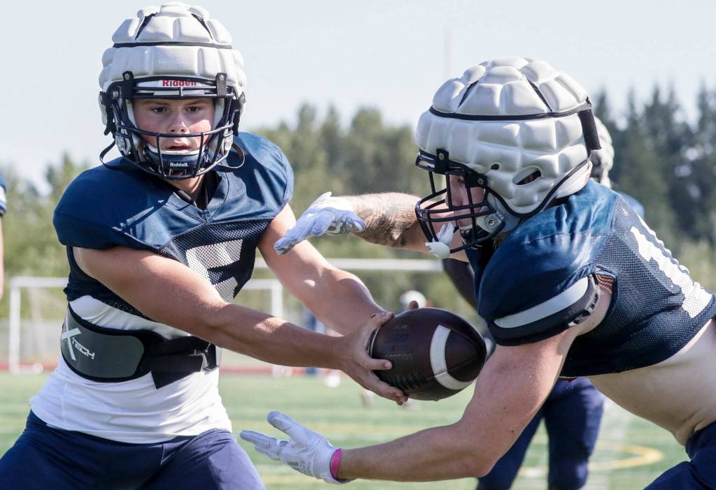 Glacier Peaks River Lien, left, hands off to Ryan King during practice Thursday afternoon at Glacier Peak High School in Snohomish. (Kevin Clark / The Herald)