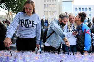 Gina Anderson (left-right) and Rae Dorcas light vigil candles as Shana Morcom gets a kiss from Tamara Cooper Tuesday afternoon at the Snohomish County Campus Plaza in Everett on August 31, 2021.  (Kevin Clark / The Herald)