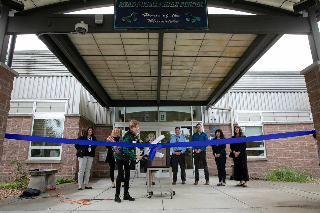 Dr. Nancy Katims, School Board Director of the Edmonds School District, cuts the ribbon during an opening ceremony of a new school health center at Meadowdale High School on Wednesday, in Lynnwood. (Ryan Berry / The Herald)