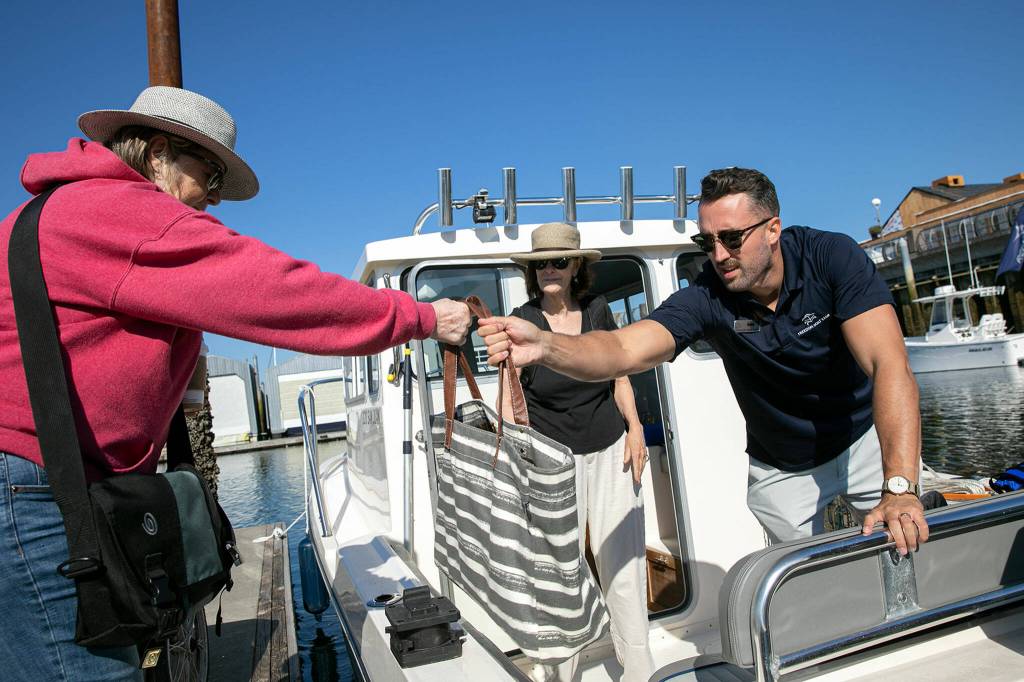 Sean Jones, membership executive of Everetts Freedom Boat Club, helps Carolyn Duncan and Anna McNally load up before setting off on the water on Aug. 11, at the Port of Everett in Everett. (Ryan Berry / The Herald)