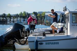 Sean Jones, membership executive of Everett's Freedom Boat Club, helps club member Carolyn Duncan load equipment onto her boat before she and a friend head out crabbing onThursday, Aug. 11, 2022, at the Port of Everett in Everett, Washington. (Ryan Berry / The Herald)