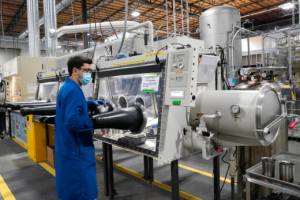 FILE - Test engineer Jacob Wilcox pulls his arm out of a glove box used for processing sodium at TerraPower, a company developing and building small nuclear reactors, Jan. 13, 2022, in Everett, Wash. A major economic bill headed to the president has “game-changing” incentives for the nuclear energy industry, experts say, and those tax credits are even more substantial if a facility is sited in a community where a coal plant is closing. Bill Gates' company, TerraPower, plans to build an advanced, nontraditional nuclear reactor and employ workers from a local coal-fired power plant scheduled to close soon. (AP Photo/Elaine Thompson, File)