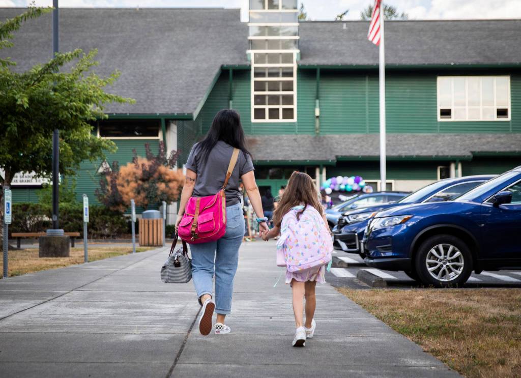 Ashly Sonneville, left, holds the hand of her daughter Sophia, 6, as they walk to school for her first day of 1st grade at Highland Elementary on Wednesday, in Lake Stevens. (Olivia Vanni / The Herald)
