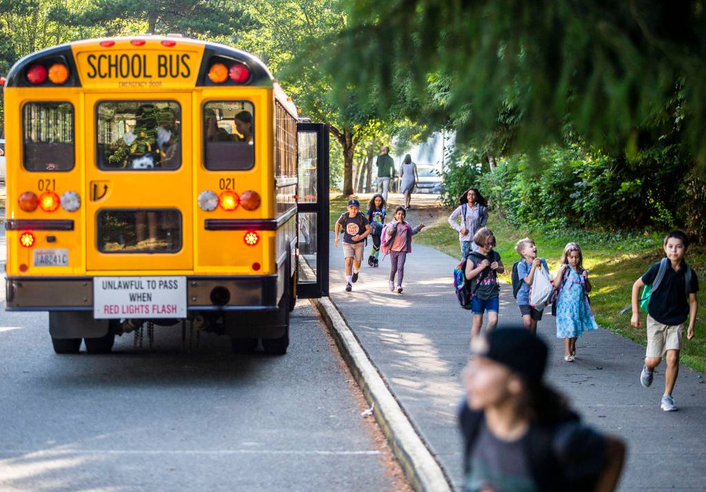 Children get off the school bus at Highland Elementary and run to class during the first day of school on Wednesday, in Lake Stevens. (Olivia Vanni / The Herald)