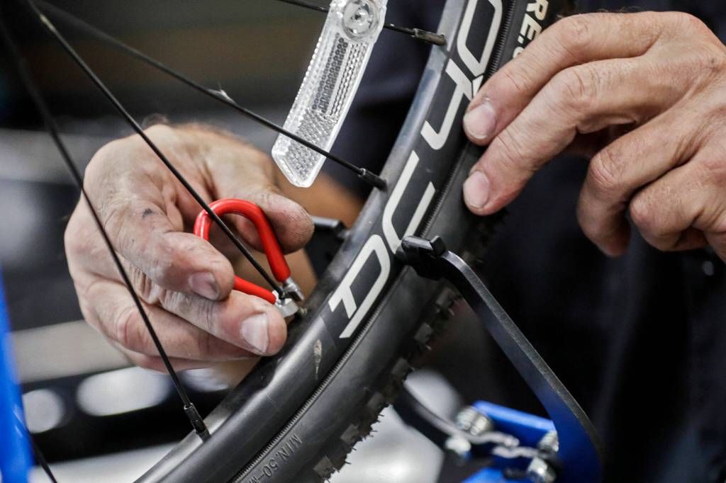 Tim Kramer works to align spokes at Bicycle Centres Wednesday in Everett, Washington on August 24, 2022.  (Kevin Clark / The Herald)