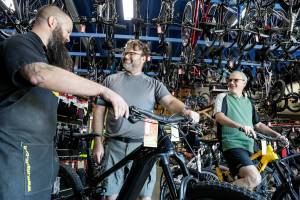 Devin Ryan, left to right, talks with Donald Whitley and Drew Yager before a test ride at Bicycle Centres Wednesday in Everett, Washington on August 24, 2022.  (Kevin Clark / The Herald)