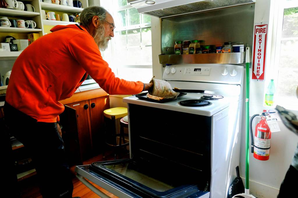 PCT thru-hiker Manny pulls out a hot pizza at Washington Alpine Clubs Guye Cabin near Snoqualmie Pass on Aug. 17. (Taylor Goebel / The Herald)
