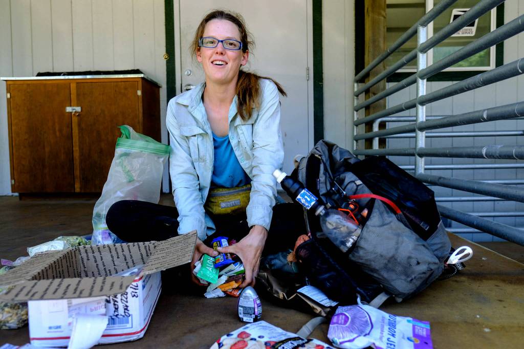 Gator, a PCT thru-hiker, organizes her next few days of meals and snacks along the Pacific Crest Trail. (Taylor Goebel / The Herald)