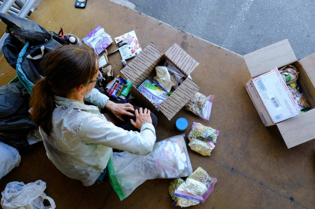 Gator, a PCT thru-hiker, packs up meals and snacks from her resupply box for the next few days at the Skykomish post office on July 28. She mailed herself dehydrated meals, dried fruits, mushroom jerky, power bars, nuts and other snacks. (Taylor Goebel / The Herald)