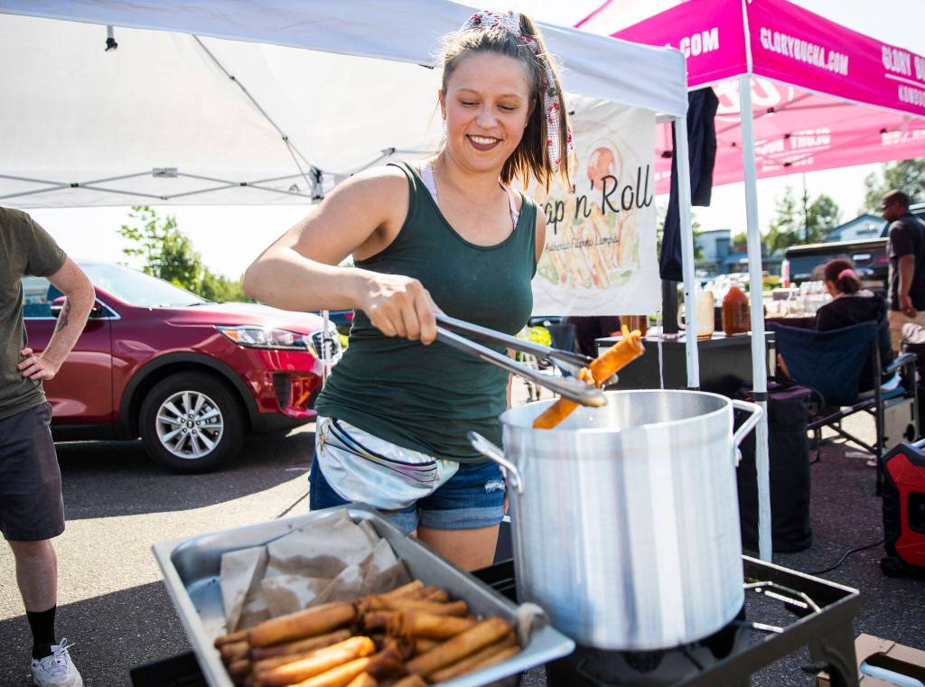 Jessica Aubert pulls freshly fried lumpia out of a pot of hot oil at the Monroe Farmers Market. (Olivia Vanni / The Herald)