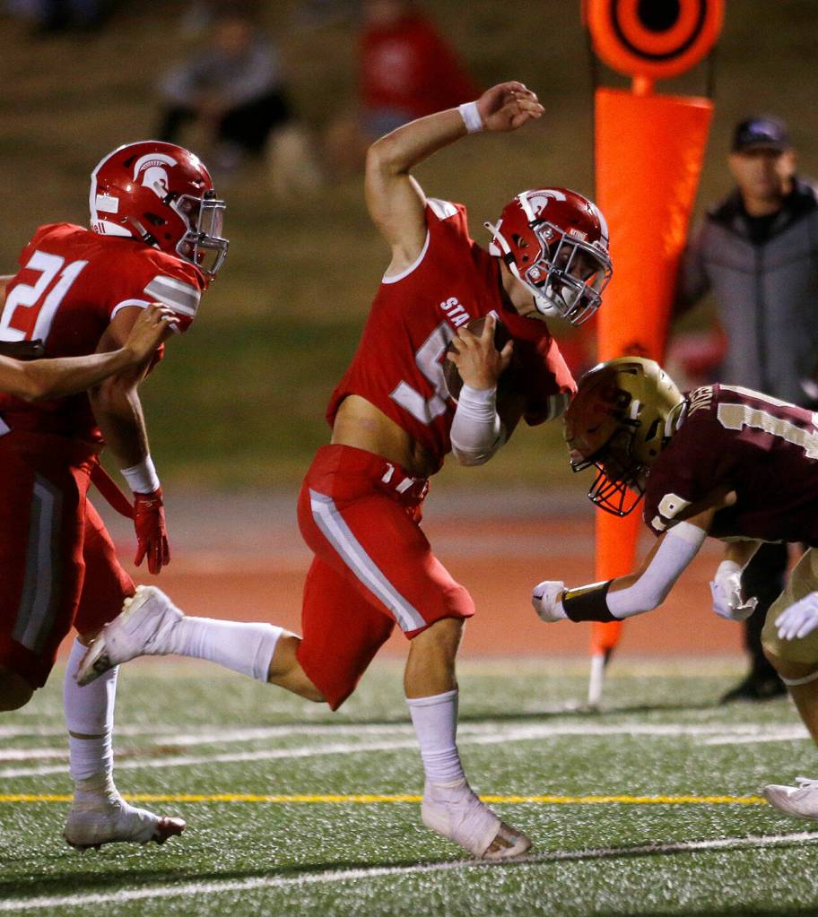 Stanwoods Ryder Bumgarner squeezes between defenders before tumbling into the end zone against Lakewood on Friday, Sep. 2, 2022, at Lakewood High School in Arlington, Washington. (Ryan Berry / The Herald)