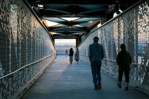 Pedestrians cross over Marine View Drive on the Grand Ave Park Bridge as the sun sets Wednesday, Sep. 7, 2022, in Everett, Washington. (Ryan Berry / The Herald)