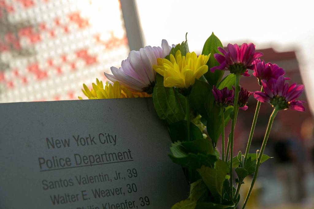 Flowers adorn the Edmonds 9/11 memorial during a ceremony to commemorate the 21st anniversary of the September 11 terrorist attacks on the U.S. on Sep. 11, 2022, outside South County Fire Station 17 in downtown Edmonds, Washington. (Ryan Berry / The Herald)
