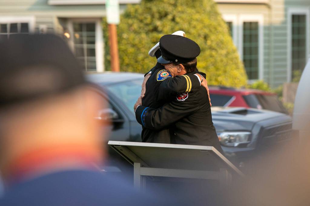 Andy Speier and Dave Erickson embrace during a ceremony to commemorate the 21st anniversary of the September 11 terrorist attacks on the U.S. on Sep. 11, 2022, outside South County Fire Station 17 in downtown Edmonds, Washington. (Ryan Berry / The Herald)