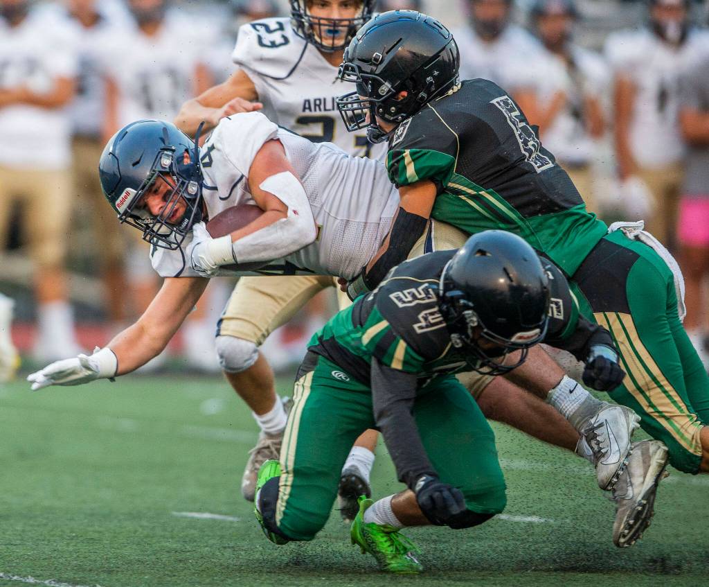 Arlingtons Spencer Fischer is tackled by multiple Marysville Getchell players during the game on Friday, Sept. 9, 2022 in Marysville, Washington. (Olivia Vanni / The Herald)