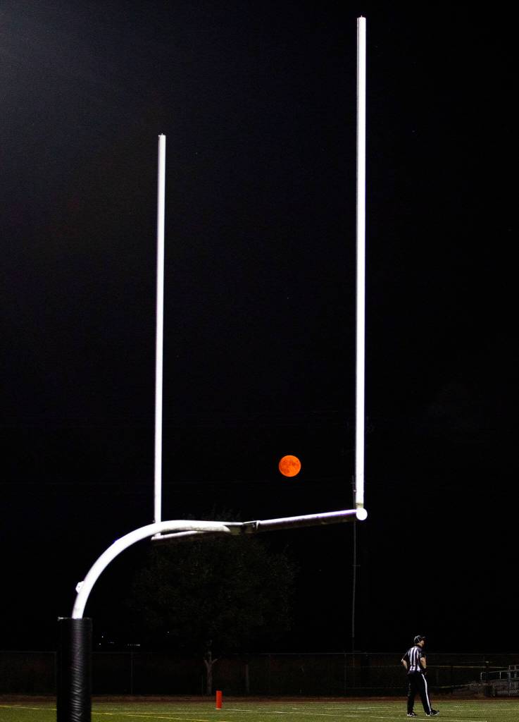 A red moon rises between the goal posts during the game between Marysville Getchell an Arlington on Friday, Sept. 9, 2022 in Marysville, Washington. (Olivia Vanni / The Herald)