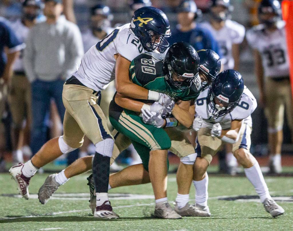 Marysville Getchells Wyatt Harris is tackled by multiple Arlington players during the game on Friday, Sept. 9, 2022 in Marysville, Washington. (Olivia Vanni / The Herald)