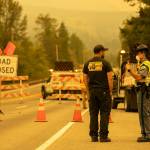 State Trooper Isaiah Oliver speaks to a BNSF worker at mile marker 31.7 as road closures and evacuations mount in response to the Bolt Creek Fire on Saturday, Sep. 10, 2022, on U.S. 2 near Index, Washington. (Ryan Berry / The Herald)