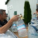 Phillip Spence, of Tractor Supply Co. in Monroe, unloads a pallet of water jugs donated by the company alongside Emilio Gomez and Michael Bilodeau on Sunday, Sep. 11, 2022, at the Evergreen State Fairgrounds in Monroe, Washington. (Ryan Berry / The Herald)