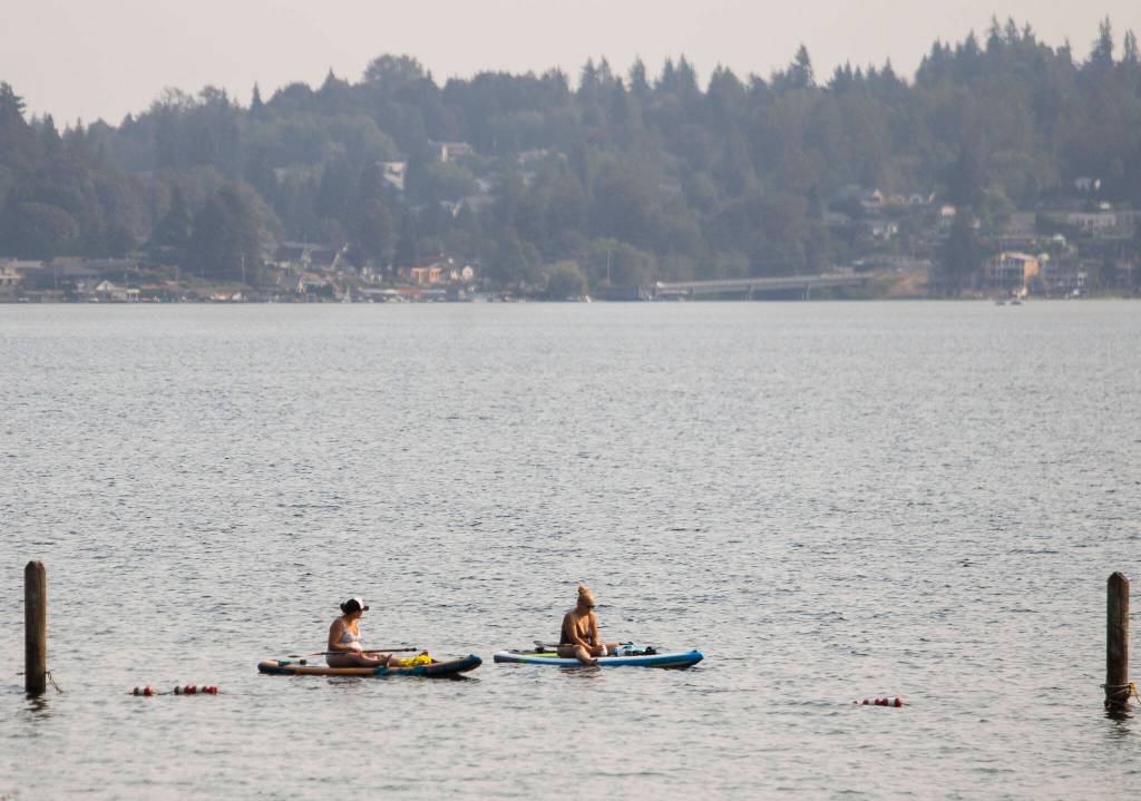 People sit on paddle boards out on Lake Stevens where smoke has settled on Friday, Sept. 9, 2022 in Lake Stevens, Washington. (Olivia Vanni / The Herald)
