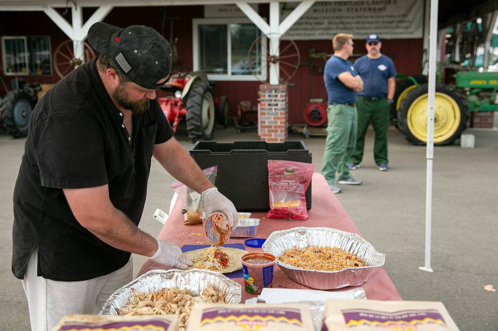Michael Long, who runs Old Truck Barbecue part time out of Lake Stevens, prepares bbq chicken burritos for emergency responders on Sunday, Sep. 11, 2022, at the Evergreen State Fairgrounds in Monroe, Washington. Long and two of his sons, Jonathan and Anthony, were expecting to feed roughly 400 people on Sunday. Long said he wanted to help during the Bolt Creek Fire because his parents lost their Oregon home to a wildfire two years ago and he wants to show emergency responders his appreciation for the work they do. (Ryan Berry / The Herald)