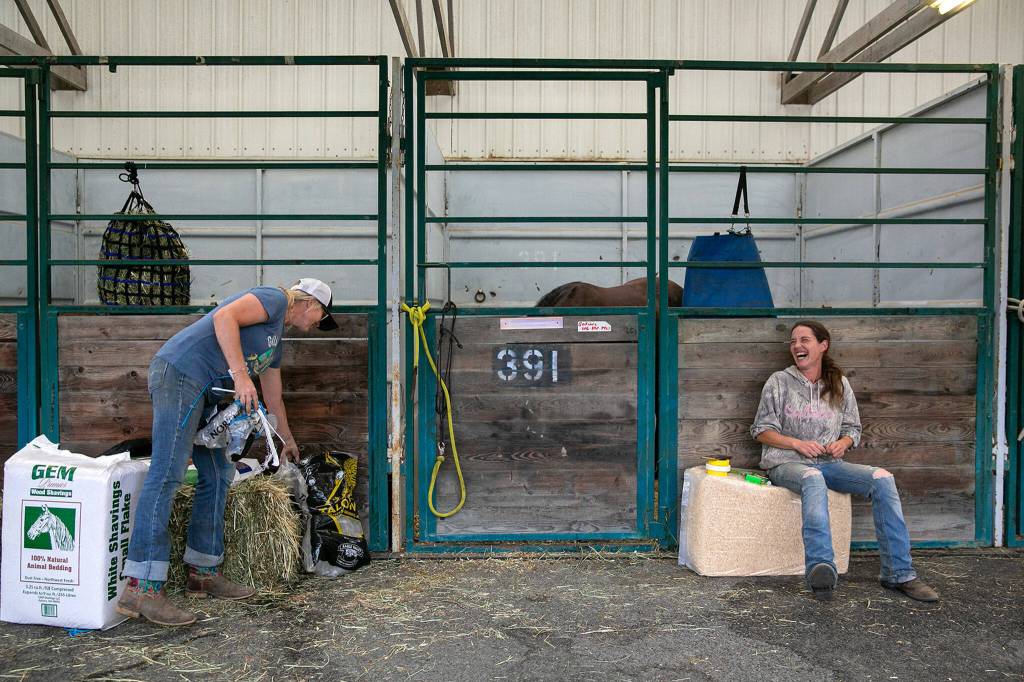 Doneatta Godinez and Nikki Prather, both of Gold Bar, take care of their horses at a stable on Sunday, Sep. 11, 2022, at the Evergreen State Fairgrounds in Monroe, Washington. Godinez brought 10 of her horses to the emergency stables at the fairgrounds in response to the Bolt Creek Fire, and Prather brought two. Both still have animals back on their properties near the site of the fire and are prepared to evacuate them as well if the flames moves closer. (Ryan Berry / The Herald)