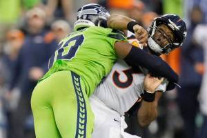 Denver Broncos quarterback Russell Wilson, right, is hit by Seattle Seahawks linebacker Uchenna Nwosu, left, after gettin a pass off during the second half of an NFL football game, Monday, Sept. 12, 2022, in Seattle. (AP Photo/Stephen Brashear)