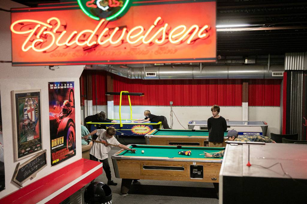 Kids play pool and air hockey while waiting to race at Traxx Indoor Raceway on Friday. (Ryan Berry / The Herald)