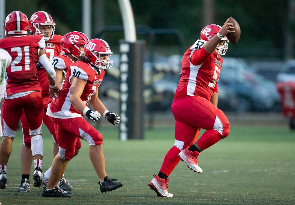 Marysville Pilchucks Malachi Meafua lifts the ball in the air in celebration after recovering a fumble during the game on Friday, Sept. 16, 2022 in Marysville, Washington. (Olivia Vanni / The Herald)