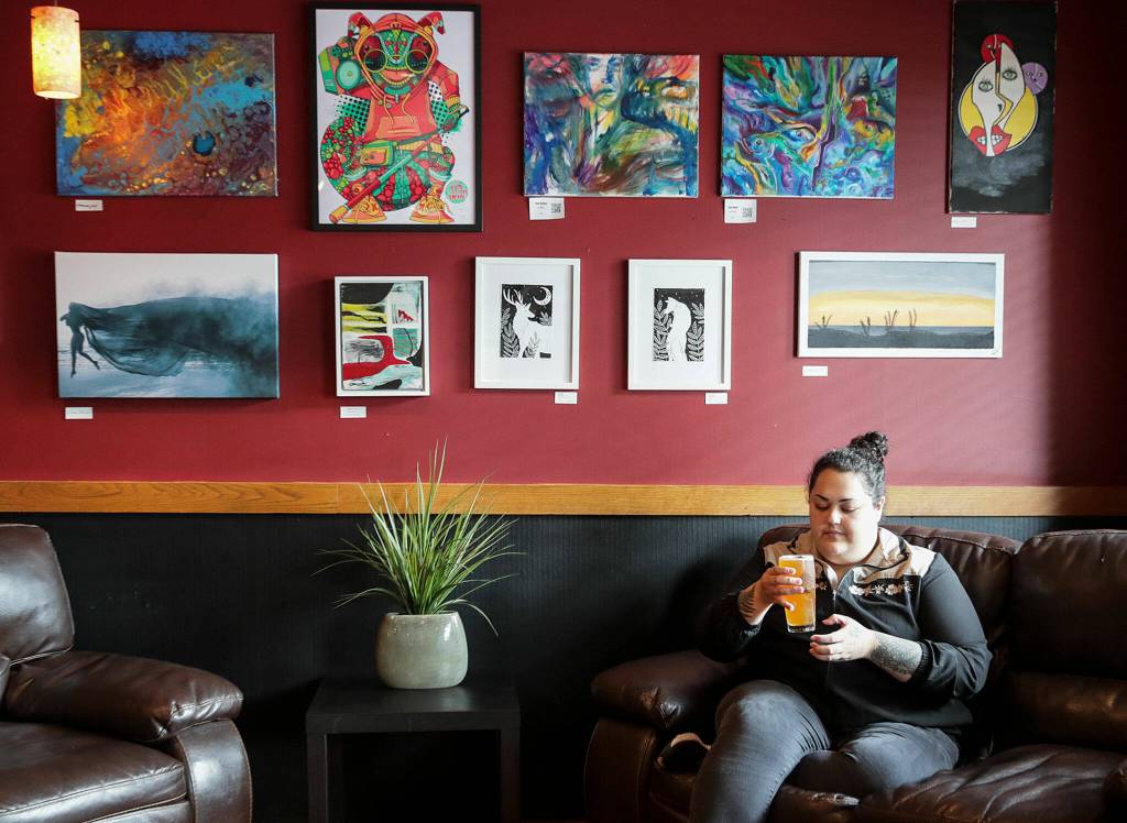 Kassandra Alcala enjoys a pint under the art gallery on Sept. 13, in Lynnwood. (Kevin Clark / The Herald)