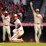 Los Angeles Angels' Shohei Ohtani, second from left, scores on a single by Taylor Ward as Luis Rengifo, left, and Matt Duffy, second from right, gestures while Seattle Mariners catcher Curt Casali watches during the first inning of a baseball game Friday, Sept. 16, 2022, in Anaheim, Calif. (AP Photo/Mark J. Terrill)