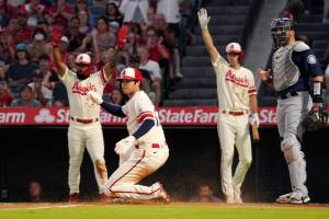 Los Angeles Angels' Shohei Ohtani, second from left, scores on a single by Taylor Ward as Luis Rengifo, left, and Matt Duffy, second from right, gestures while Seattle Mariners catcher Curt Casali watches during the first inning of a baseball game Friday, Sept. 16, 2022, in Anaheim, Calif. (AP Photo/Mark J. Terrill)