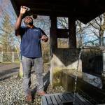 Alderwood Water & Wastewater District water quality tech assistant Matt Williams looks at the clarity of a water sample taken from the artesian well located along164th Street on Monday, April 2, 2018 in Lynnwood, Wa. The well," also known as Well No. 5 or the 164th Street Artesian Well is in excess of 400 feet in depth and flows at a rate of about 10 gallons per minute. (Andy Bronson / The Herald)