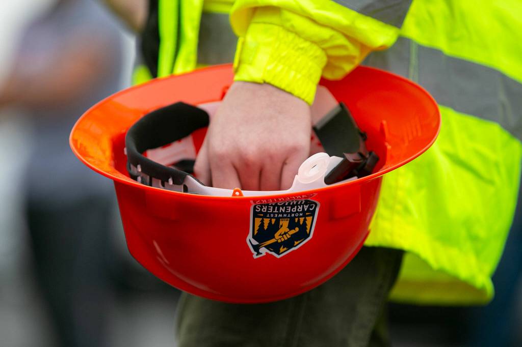 A pre-apprentice holds a hardhat featuring the Northwest Caarpenters Union logo during the grand opening of the Northwest Carpenters Institutes new building on Thursday, in Burlington. (Ryan Berry / The Herald)