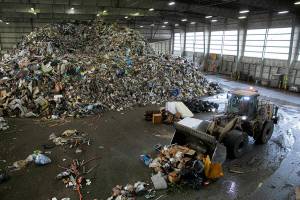A worker maneuvers a front-end loader around a gigantic pile of garbage Friday, April 29, 2022, at the Airport Road Recycling and Transfer Station in Everett, Washington. (Ryan Berry / The Herald)